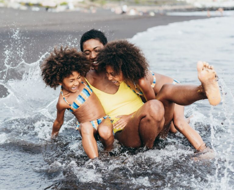 mom and two daughters playing in the ocea