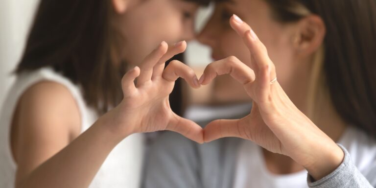 young girl and mom making heart with hands