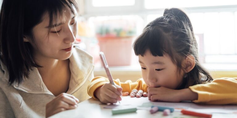 asian mom and daughter coloring at table